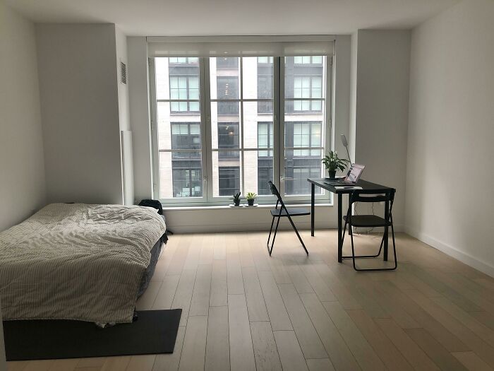 Minimalistic room with a bed and desk, illustrating poorly-aging interior design trends to avoid.