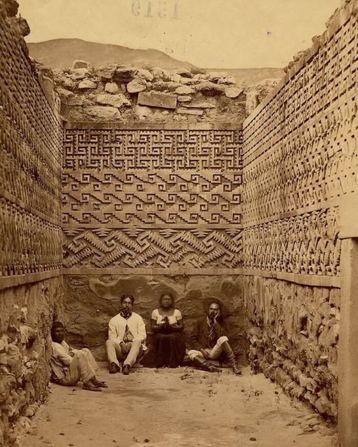 Intricate ancient civilization wall designs with four seated individuals, showcasing historic architectural artistry.
