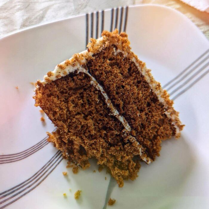 A slice of old-school delicacy cake with cream filling on a striped plate.