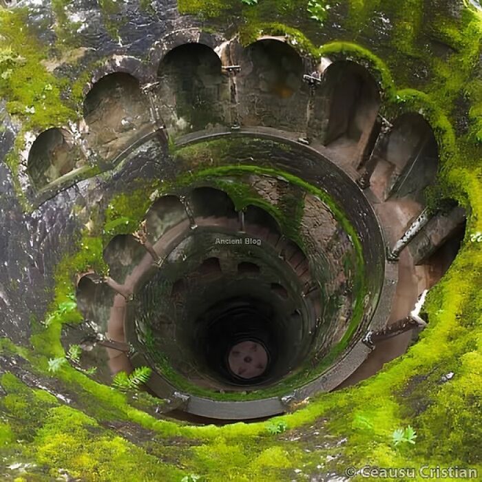 Ancient architectural structure resembling an inverted tower, surrounded by mossy walls and arches.