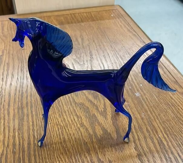 Blue glass horse figurine found while thrifting, placed on a wooden table.