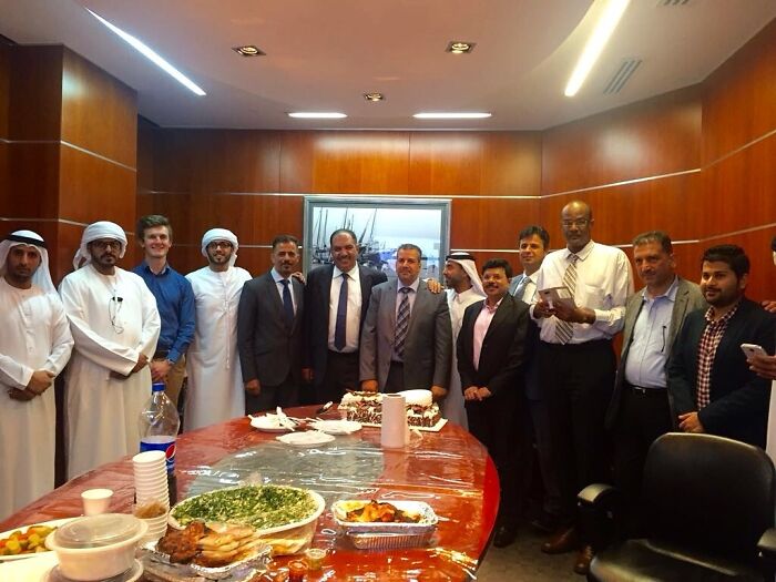 Group of people in formal attire posing at a table with dishes, capturing a unique event moment.