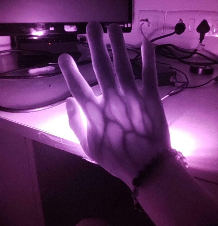 A hand illuminated by purple light casting unique shadows, showcasing an awesome aspect of our world.