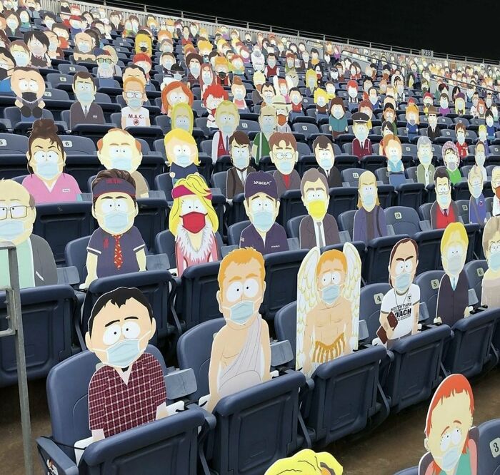 Cardboard cutouts of cartoon characters wearing masks fill a stadium's seating area.