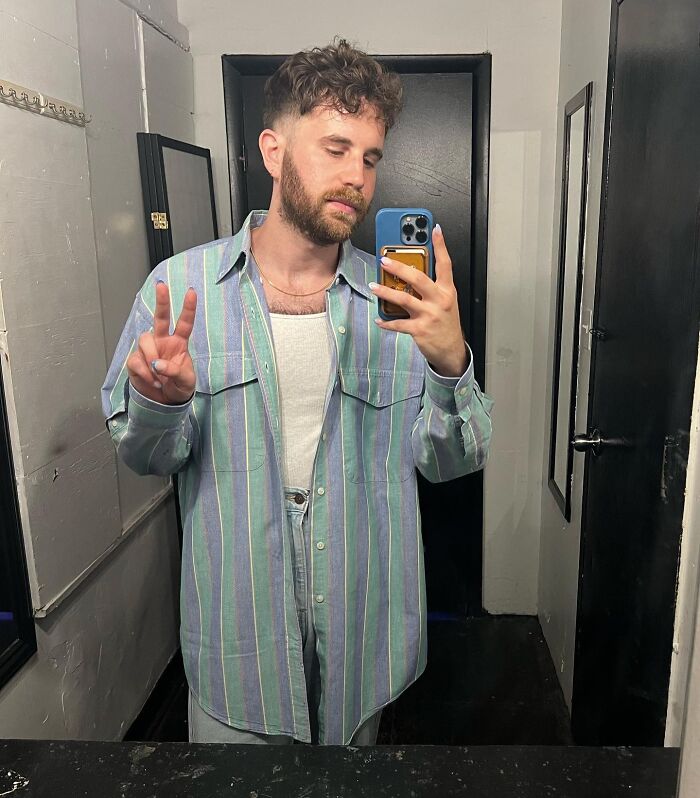 Person taking a mirror selfie in a striped shirt, highlighting not-self-made-celebs theme.