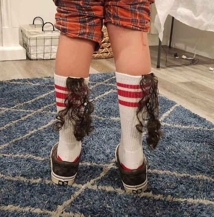 Child wearing socks with faux hair attached, standing on a blue rug, showcasing an Amazon find.