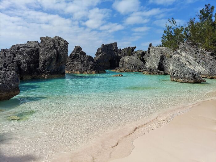 Stunning beach with clear blue water and rocky cliffs under a blue sky.