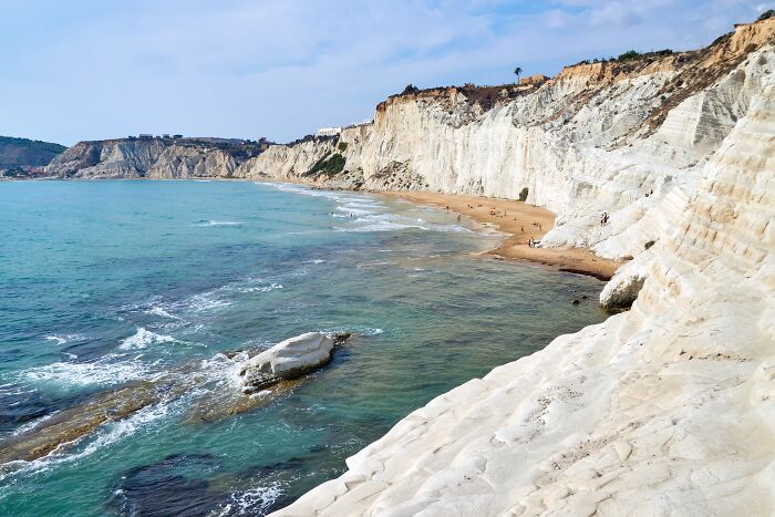 Stunning beach with turquoise waters and dramatic white cliffs under a clear blue sky.