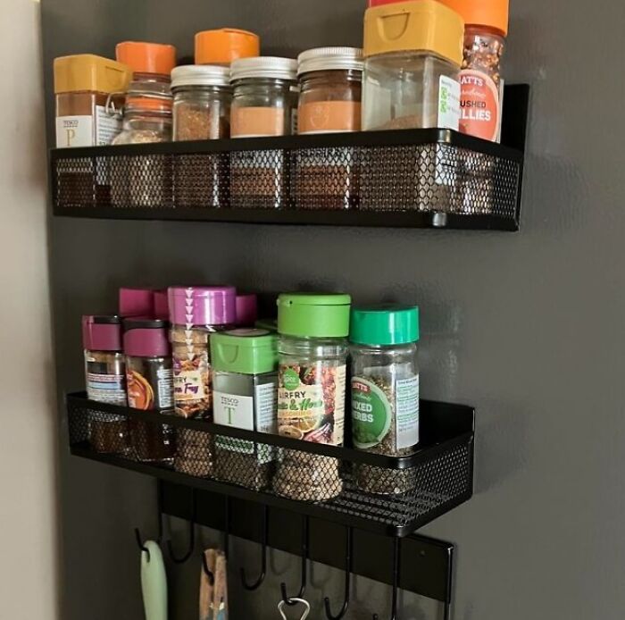 Wall-mounted spice racks filled with assorted jars, showing a tidy kitchen organization solution.
