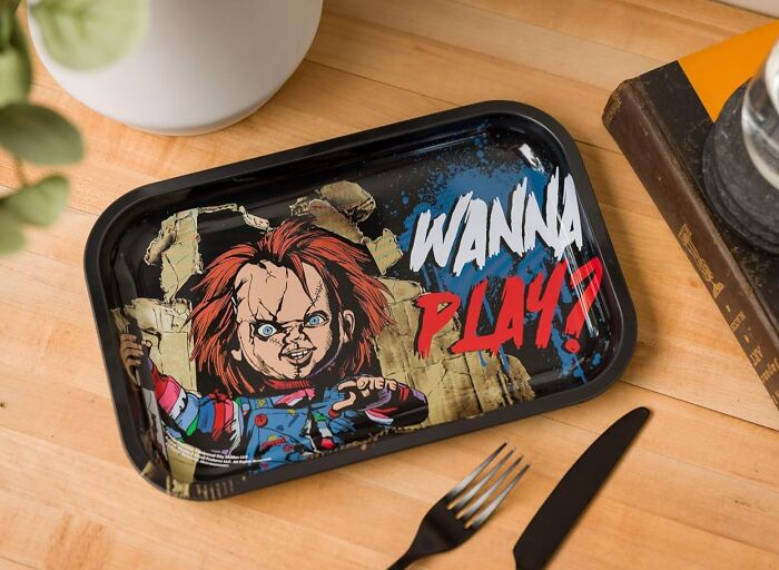 Chucky-themed tray with "Wanna Play?" text, embodying pure fandom goals on a wooden table with cutlery nearby.