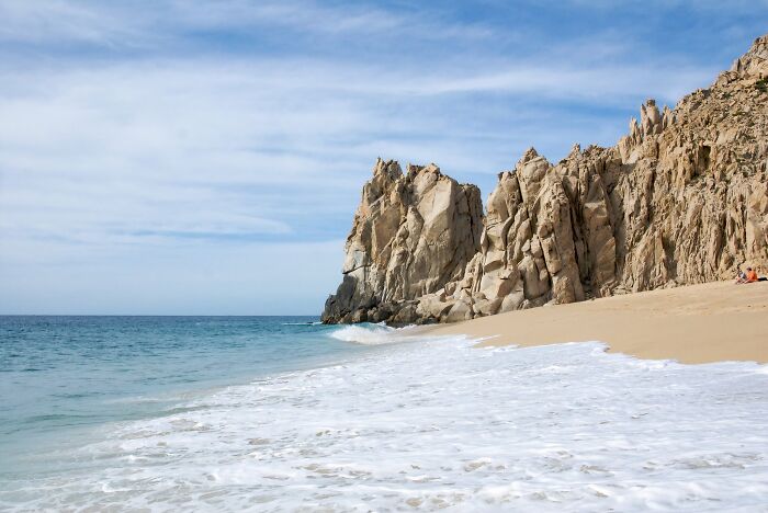 Majestic cliffs by the sea on a stunning beach with gentle waves lapping the sandy shore.