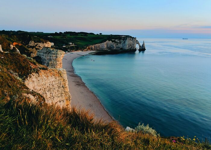 Scenic beach with dramatic cliffs and calm sea at sunrise, offering a stunning view perfect for travel inspiration.