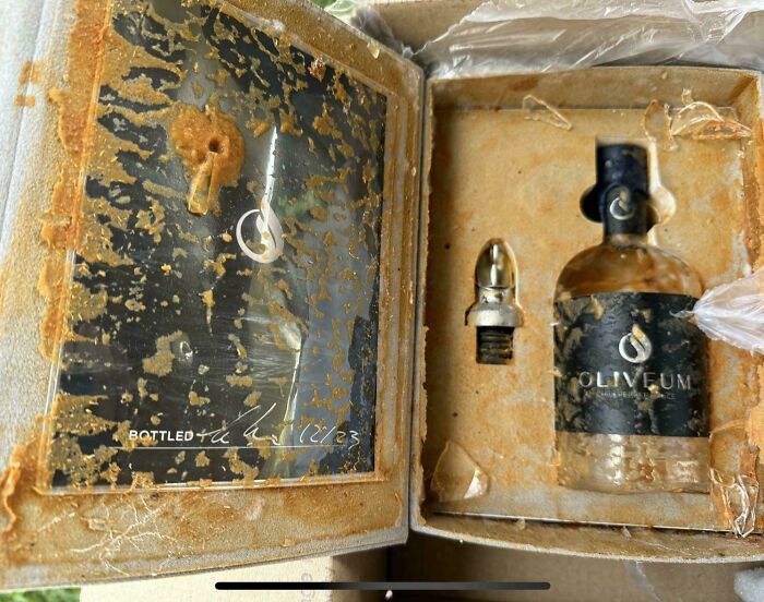 Damaged box with a leaking bottle of Olivefum oil, misfortune evident.