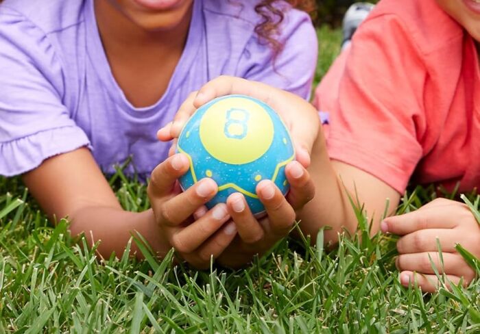 Children holding a colorful Easter egg with number 8 on the grass, showcasing fun Easter ideas.