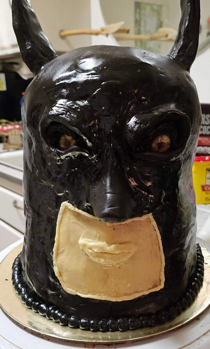 Bat-themed cake with shiny black frosting in a kitchen, representing a humorous baking fail.