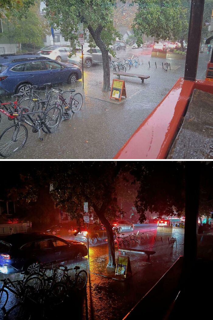 Calle inundada por la lluvia, bicicletas y coches aparcados, escena surrealista bajo las luces urbanas.