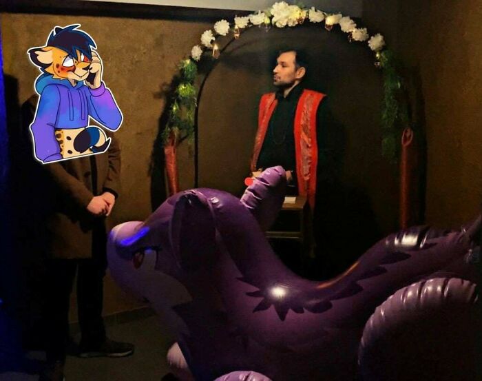 A person with a cartoon face and an inflatable purple creature in an awkward ceremony setting.