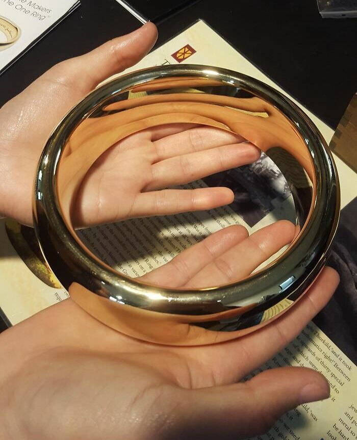 Hands holding a reflective metal ring displaying intriguing optical effects, showcasing our boring-free world.