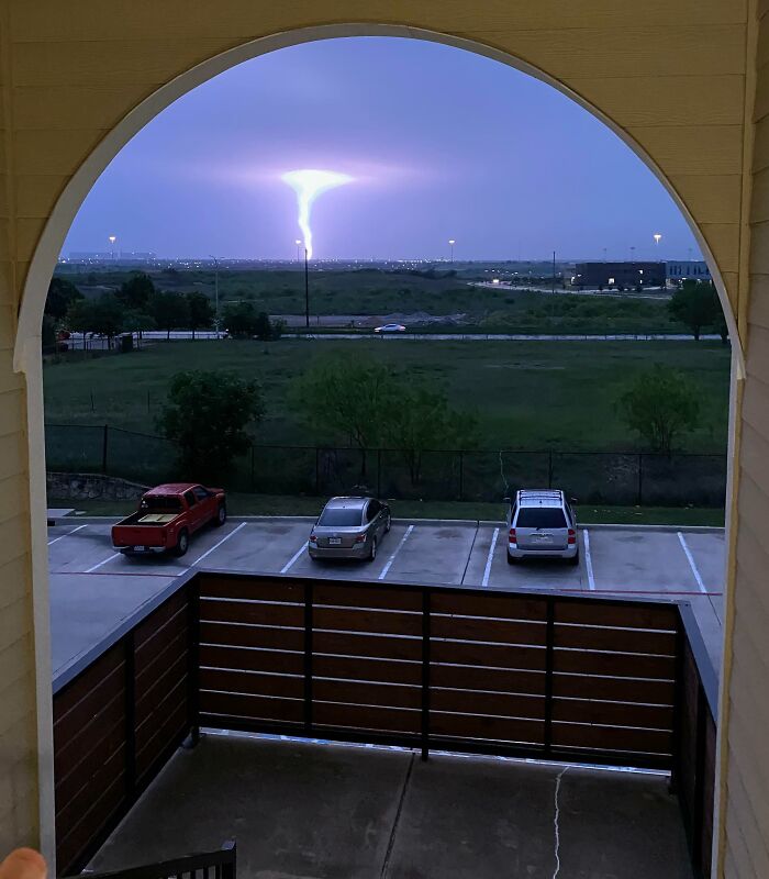 Vista surreal de un rayo en el horizonte desde un balcón al anochecer.