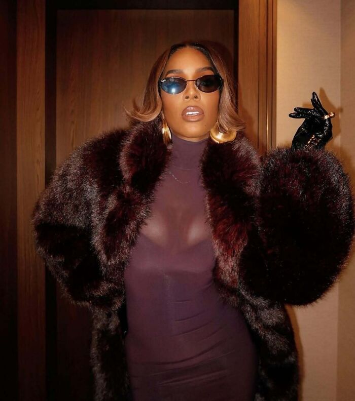 Celebrity in fur coat and sunglasses, posing glamorously.