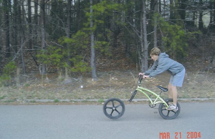 Person riding a unique bike with front wheels much larger than the rear, demonstrating an unusual moment.