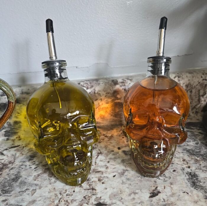 Skull-shaped oil and vinegar dispensers on a marble countertop, showcasing a weird kitchen accessory.