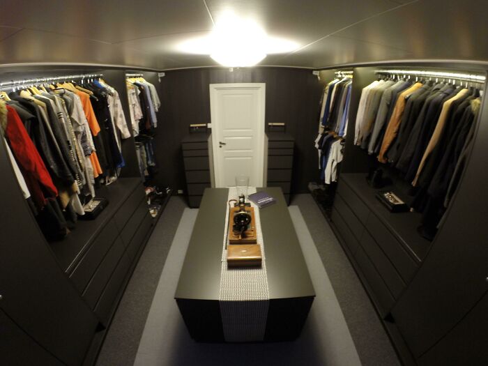 Walk-in closet with modern black cabinetry, hanging clothes, and a central island, highlighting interior design trends to avoid.