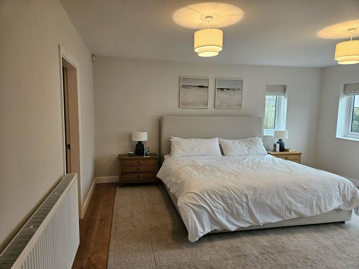 Minimalist bedroom with neutral tones and simple furniture illustrating poorly-aging interior design trends.