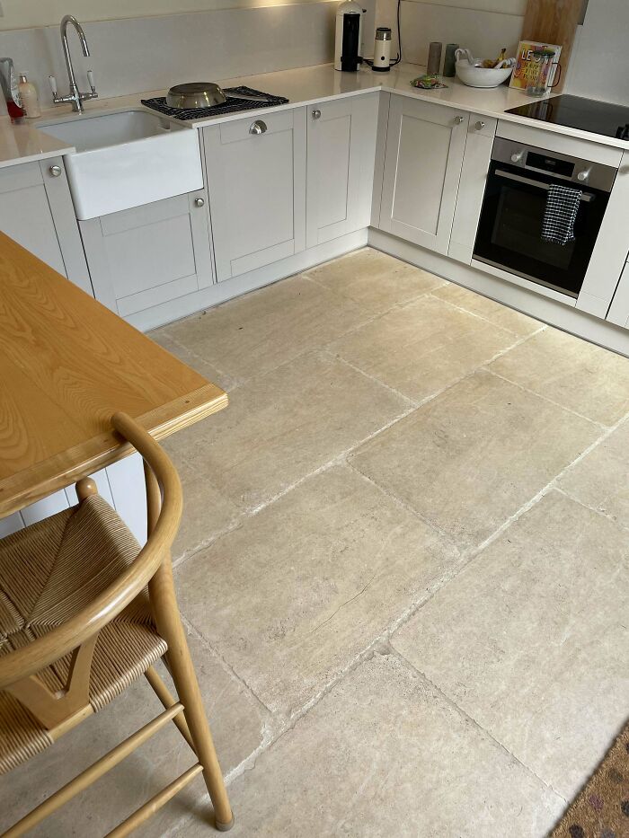 Modern kitchen with white cabinetry and aged stone tile flooring illustrating poorly-aging interior design trends.