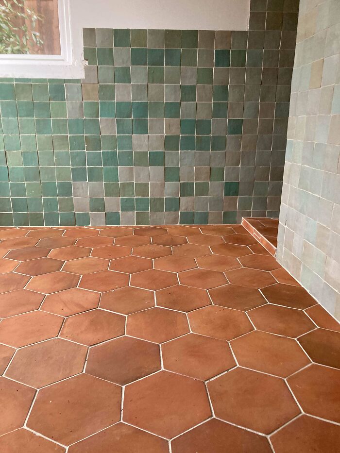 Terracotta hexagonal floor tiles with green and gray square wall tiles in an interior design trend to avoid.