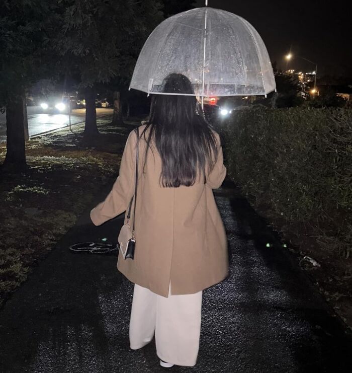Woman with a transparent umbrella walks at night, highlighting unknown job tasks.