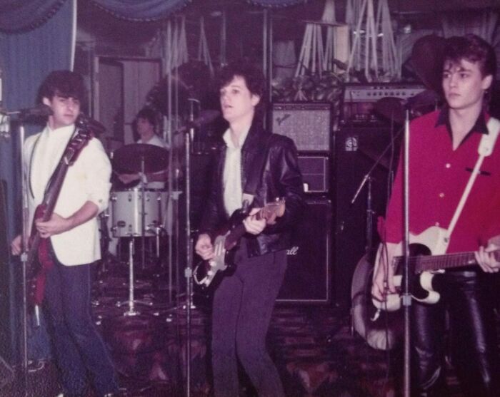 Band performing live on stage with guitars and drums, capturing an authentic moment.