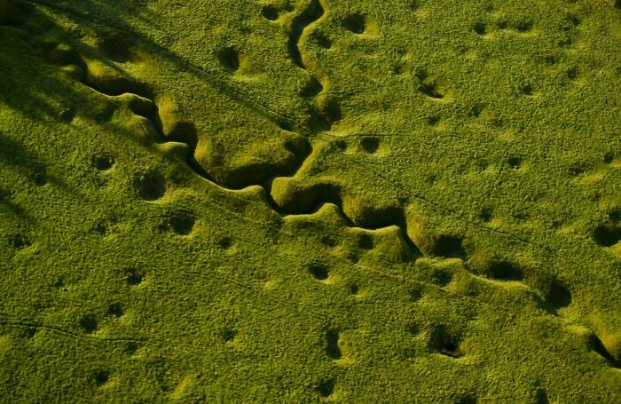 Aerial view of grassland with erosion patterns, showcasing transformation by time and use.