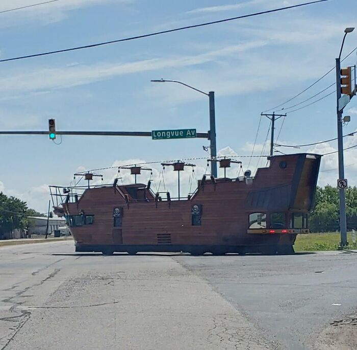 A pirate ship-shaped vehicle crosses an intersection at Longvue Ave under a clear sky.