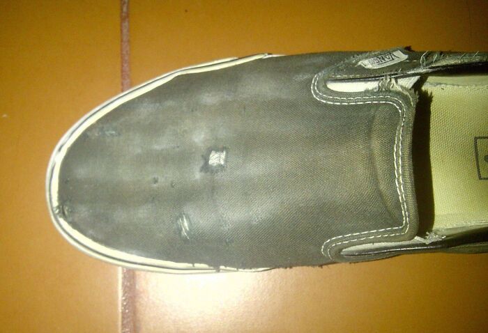 Worn-out shoe showing signs of transformation by time and use on a tiled floor.