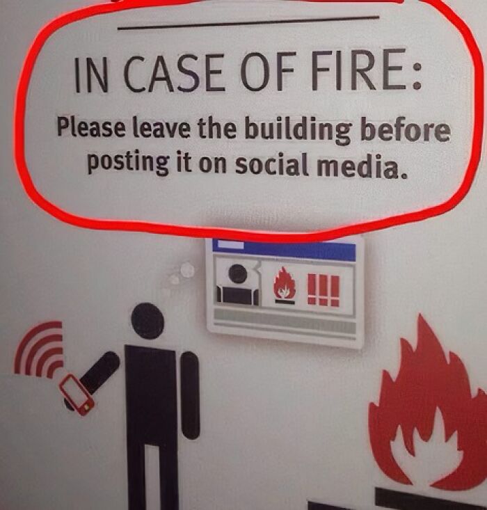 Fire warning sign humorously advising evacuation before social media posts.