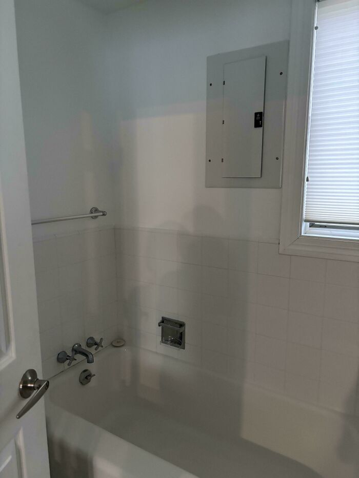 Electrical panel dangerously installed above bathtub, posing a safety hazard.