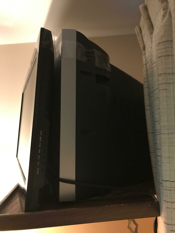 CRT monitor awkwardly fixed with tape on a shelf, showcasing a repair fail.
