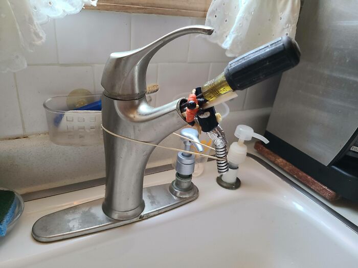 DIY faucet repair fail with screwdriver and tape in a kitchen sink setting.