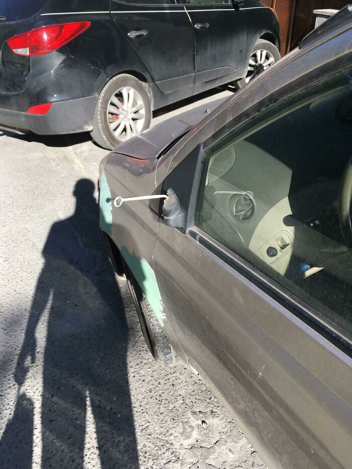 Car mirror repair attempt with zip ties, highlighting a funny repair fail.