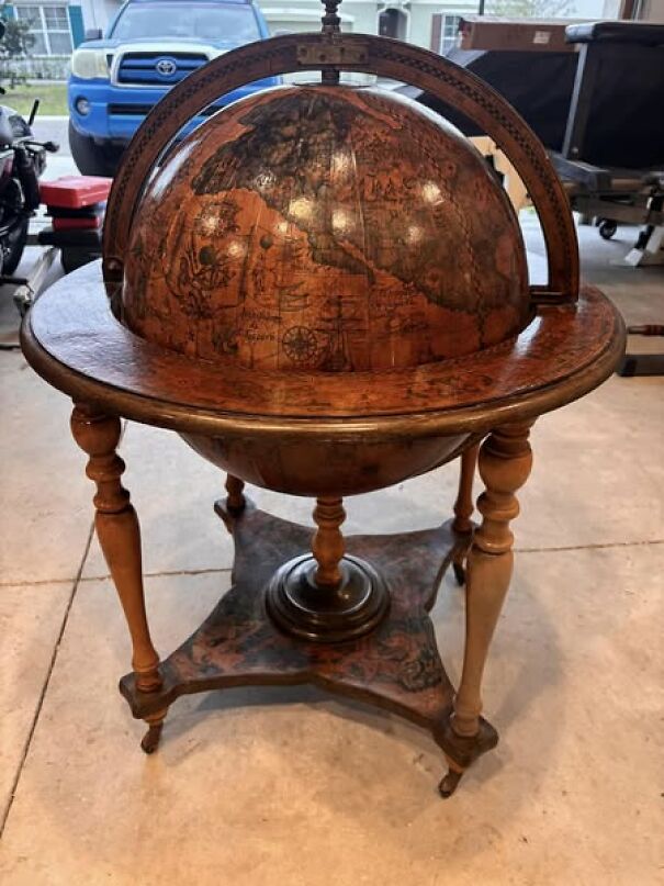 Antique globe on wooden stand, a unique thrift find with vintage map details in a garage setting.