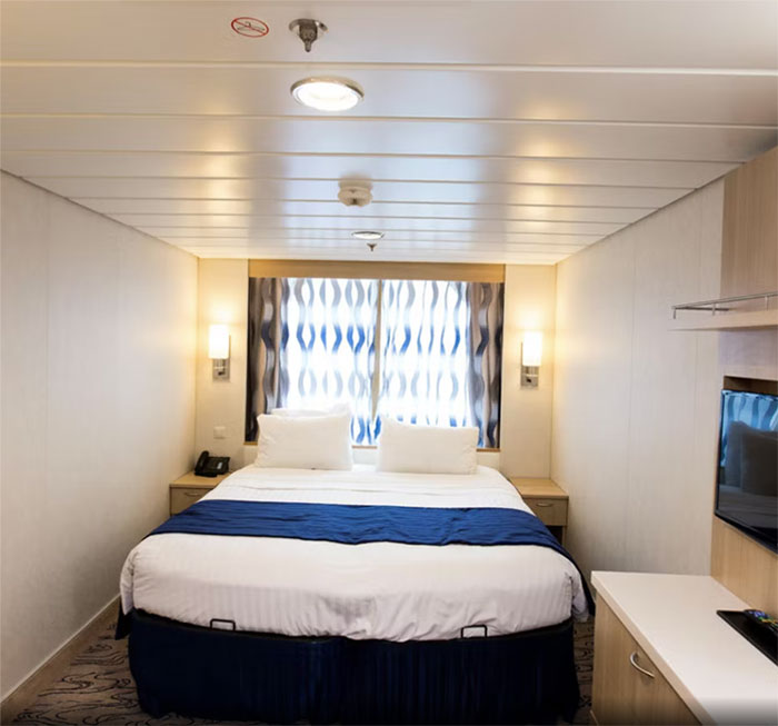 Cruise ship cabin interior with a bed and blue accents, representing a tragic fall at sea involving '80s rocker fianc&eacute;e.
