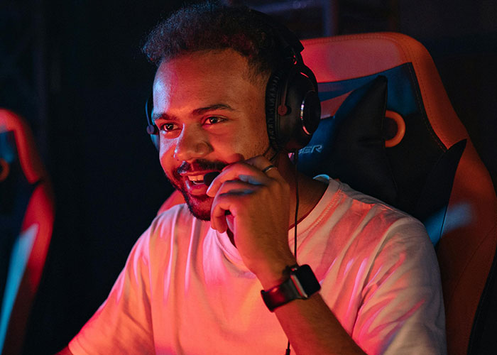 Person in a gaming chair, wearing headphones, smiling, representing positive reactions to coming out of the closet.