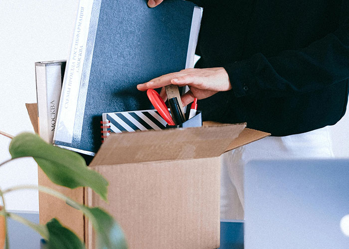 Employee packing personal items into a box, a sign of a toxic workplace environment.