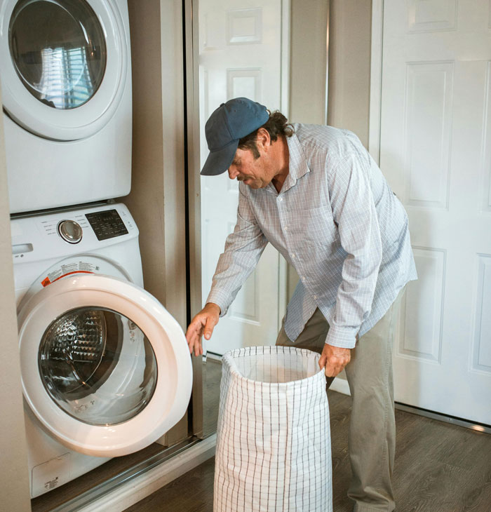 Man doing laundry at home with a front-loading washing machine.
