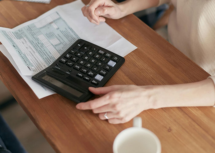 Hands using a calculator on a wooden table with documents, illustrating life without social media for Gen X.