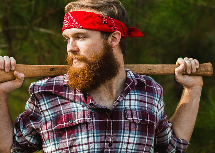 Bearded man in a plaid shirt and red bandana holding an axe, embodying memorable dad stories.