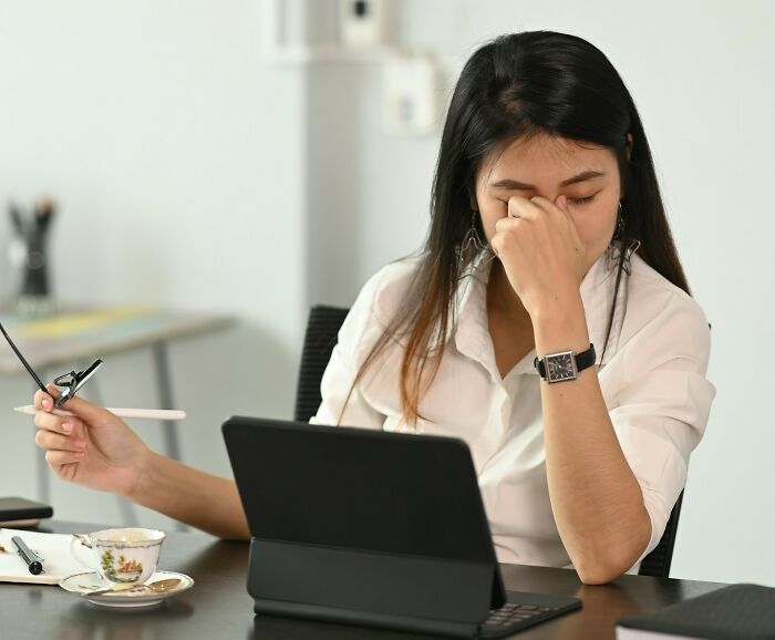 Stressed person in white shirt during a challenging job interview at office desk.