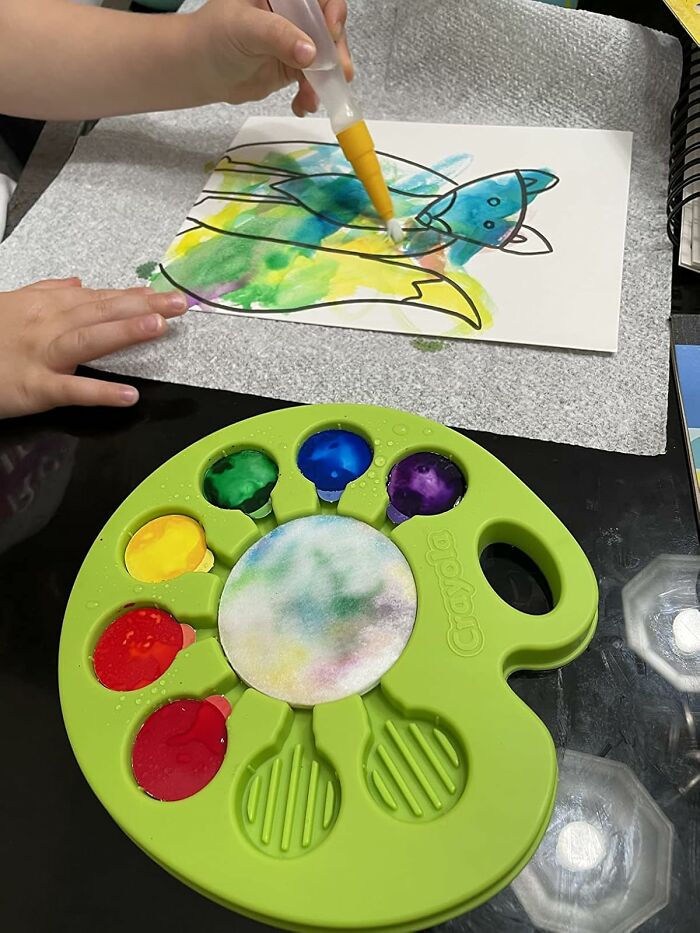 Child painting with watercolors, a creative Easter basket stuffer idea, featuring vibrant colors on paper.