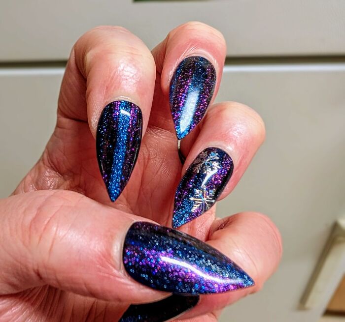 Glittery, galaxy-themed nails showcase trendy spring style with vibrant blue and purple hues.